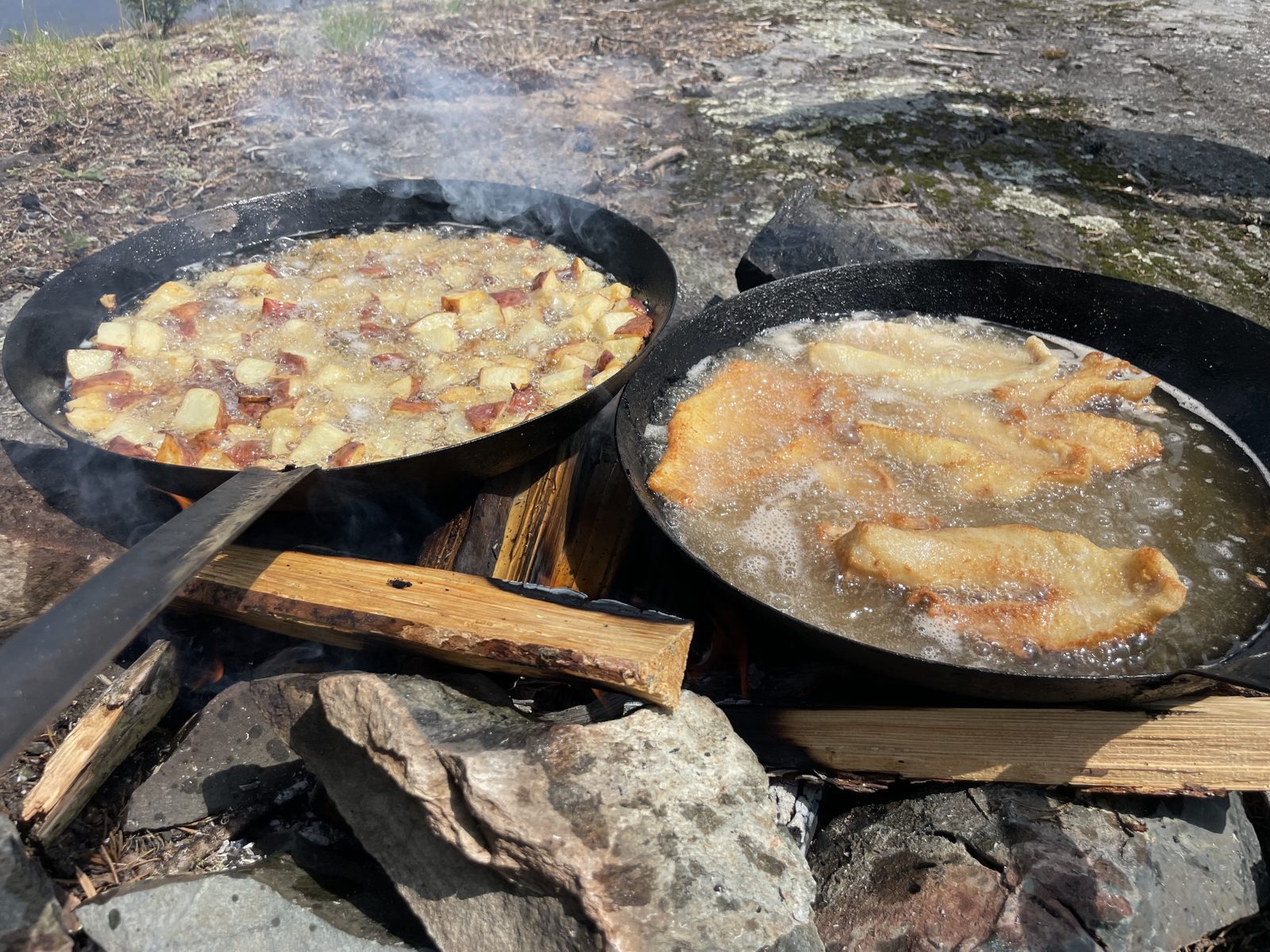 Shore lunch cooking over a fire at Canada North Lodge